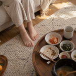 명절 상 옆 소파에서 맨발을 러그 위에 내려놓은 모습과 남은 반찬이 놓인 낮은 상을 위에서 내려다본 장면