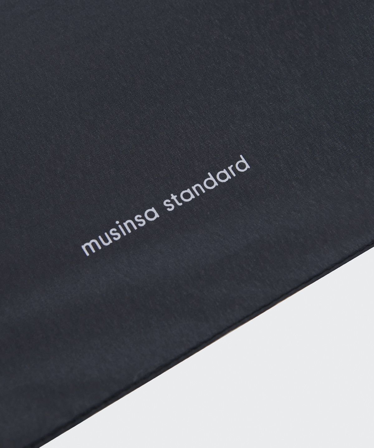 우산 천 위에 흰색 글자로 인쇄된 musinsa standard 로고 클로즈업