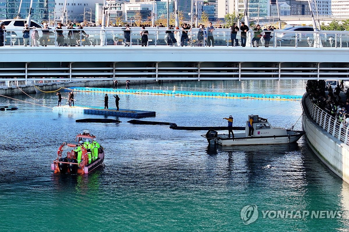 수로에서 유도작업을 하는 해경 보트와 폰툰, 지켜보는 시민들